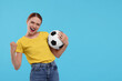 © New Africa - Emotional fan holding football ball and celebrating on light blue background, space for text