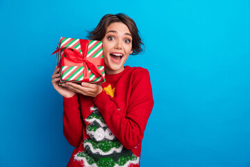 Poster - Photo of positive girl holding package gift give on christmas event party isolated blue color background