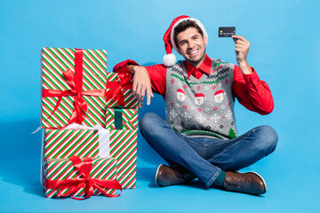 Poster - Full length photo of nice young male credit card shopping presents wear x-mas print vest hat garment isolated on blue color background