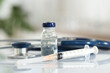 © New Africa - Glass vial, syringe and stethoscope on white table, closeup
