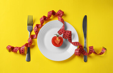 Poster - Plate with half of tomato, cutlery and measuring tape on yellow background, flat lay. Diet concept