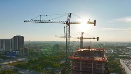 Wall Mural - Tower lifting cranes at high residential apartment building construction site. Real estate development in Miami urban area