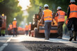 Road construction workers and road construction machinery make new asphalt road pavement. Working concept of construction and construction.