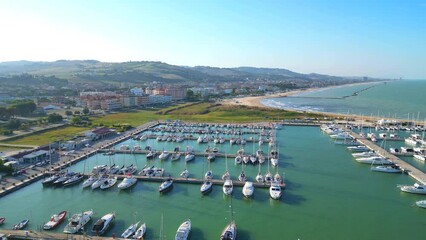 Wall Mural - Establishing aerial truck left and pan right shot with a wide view stretching from the southern Port of Porto San Giorgio to the northern skyscrapers standing between buildings, hills and the Adriatic