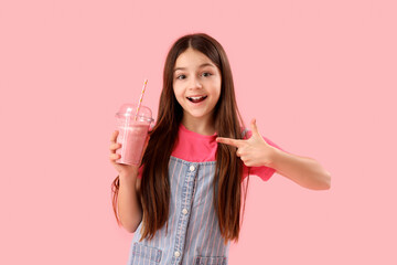 Wall Mural - Little girl pointing at glass of smoothie on pink background