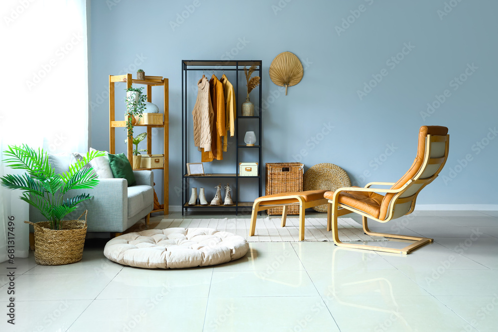 Interior of light room with shelving units, clothes and sofa