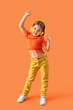 canvas print picture - Cute little girl in headphones dancing on orange background