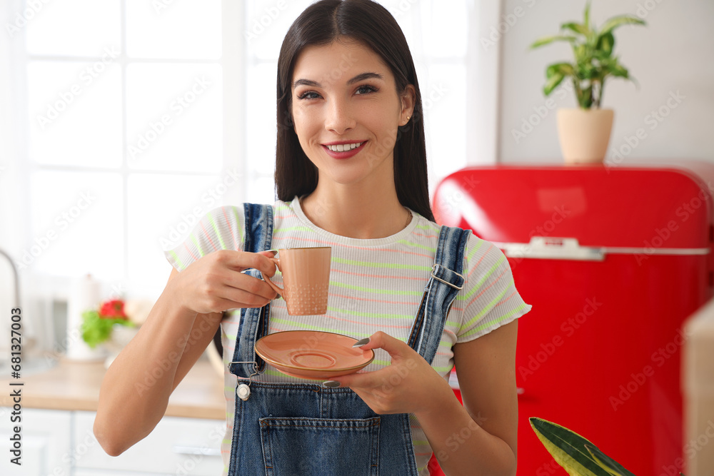 Young woman with cup of hot coffee in kitchen