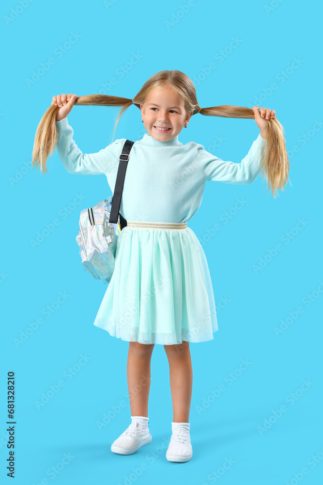 Cute little girl with backpack on blue background