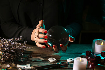 Wall Mural - Witch with crystal ball at dark wooden table, closeup