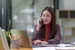 © Premreuthai - Asian businesswoman talking on the phone professionally in her office.