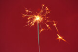 Fototapeta Dmuchawce - Beautiful Christmas sparkler on red background