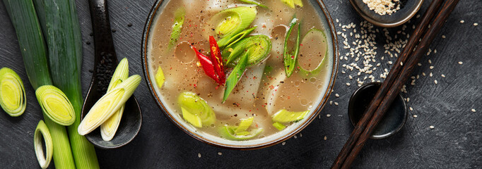 Wall Mural - Bowl of leek soup with chili pepper on dark background. Food concept