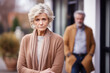 Senior blonde woman feeling sad and disappointed, her husband is behind