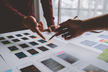 ux developers and ui designers brainstorm on tabletop mobile app layout design planning design color coding at modern office Creative digital development agency.