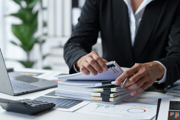 Wall Mural - Asian businesswoman searches through piles of financial documents to make calculations Marketing analysis Tax administration Statistical accounting report on the desk in the office office.