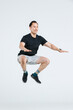 © Bangkok Click Studio - Isolated cutout full body studio shot of strong focus Asian male fitness athlete sportman model in black casual sport workout outfit sneakers posing jumping high in air exercising on white background