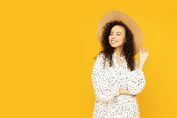 Wall Mural - Young attractive girl in a hat on a yellow background