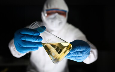 Wall Mural - Male chemist hold test tube with yellow liquid biological research closeup. Conducts study urine materials content harmful substances microorganisms human heretical cloning concept