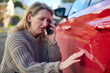 Unhappy Mature Female Driver With Damaged Car After Accident Calling Insurance Company On Mobile Phone