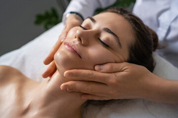 Wall Mural - Shot of a beautiful young woman enjoying face massage at the beauty salon. Serene woman relaxing outdoor in a beauty center.