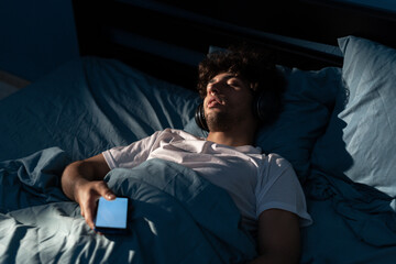 Wall Mural - Arab man sleeping in bed at night with a smartphone suffers from social media addiction.