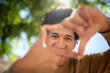 © mimagephotos - Close up smiling hispanic man framing with hands and fingers