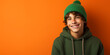 © mr_marcom - teenager boy student smiling with green hat and hoodie on orange background