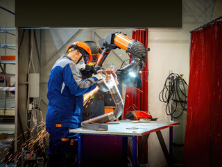 Men work in pipe production. Factory workers prepare pipeline for gas infrastructure. Men process pipe with circular saw. Two factory workers near smoke extraction machine. Production of water pipes