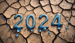 Napis 2024 tworzony przez wodę na suchej, spękanej ziemi. Motyw pogłębiającej się globalnej suszy, ochrony środowiska i zasobów wodnych