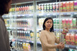 © Johnér - Couple standing in supermarket and talking while shopping