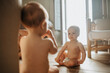 © Johnér - Shirtless baby siblings sitting on floor at home