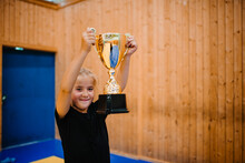 Portrait Of Smiling Girl Showing Trophy In Sports Court