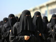 a group of Arab women wearing veils in the desert holding a demonstration