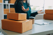 © Sirikarn Rinruesee - Startup SME small business entrepreneur of freelance Asian woman wearing apron using laptop and box to receive and review orders online to prepare to pack sell to customers, online sme business ideas.