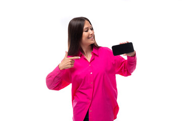 Wall Mural - portrait of a cheerful european young lady with black hair in a crimson shirt with a smartphone in her hand