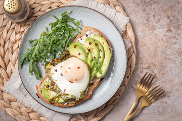 Wall Mural - Avocado egg sandwich. Healthy light breakfast concept. Whole grain toasts with avocado and fried pesto eggs