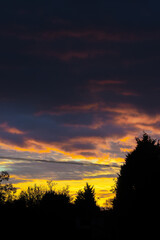 Wall Mural - Stormy colourful skies with clouds and black silhouettes