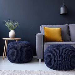 Two knitted poufs near dark blue corner sofa. Scandinavian home interior design of modern living room. 