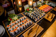 Sushi bar among catering banquet table. Variety of snacks, appetizers, seafood and cooked meals displayed as buffet for wedding, Christmas, business corporate, birthday party or other event