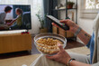 © Mediaphotos - Close-up of woman using remote control while watching movie with popcorn in the room