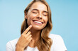 © Maria Vitkovska - Closeup portrait smiling beautiful  woman pointing finger on white teeth isolated on blue background. Advertisement, health care dental  concept