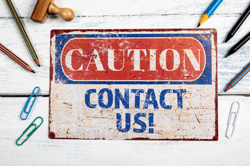 Canvas Print - contact us. metal caotion plate with text on a white wooden background