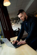 © Vadim - A man sitting at a table using a laptop computer. The Productive Pursuit: A Man Engrossed in Work on His Laptop