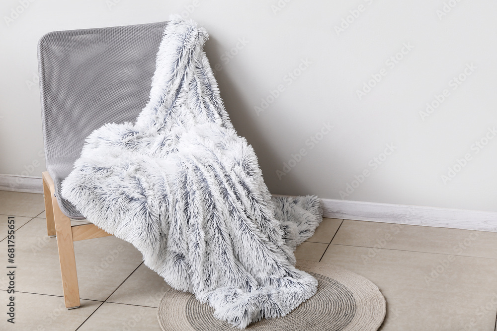New soft blanket on armchair near light wall in room