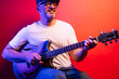 © karrastock - Man playing electric guitar on red background