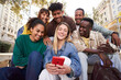 © CarlosBarquero - Diverse group of university friends sitting on stairs in street city. Happy students using and looking smartphones while smiling thrilled and excited. Chatting and commenting fun things in mobiles.