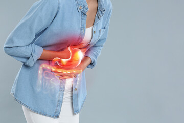 Poster - Woman suffering from stomach ache on grey background, closeup with space for text. Illustration of unhealthy gastrointestinal tract