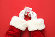 Leinwandbild Motiv Santa hands with gift card on red background, closeup