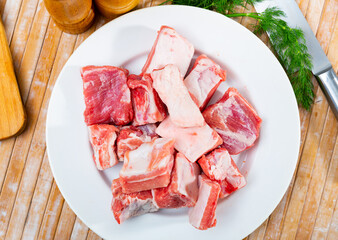 Wall Mural - Fresh pork ribs on a white ceramic plate on a table, close-up